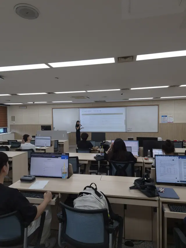 컴퓨터 실습실에서 수강생들이 노트북을 펴고 앞쪽 화면의 강의를 듣는 모습